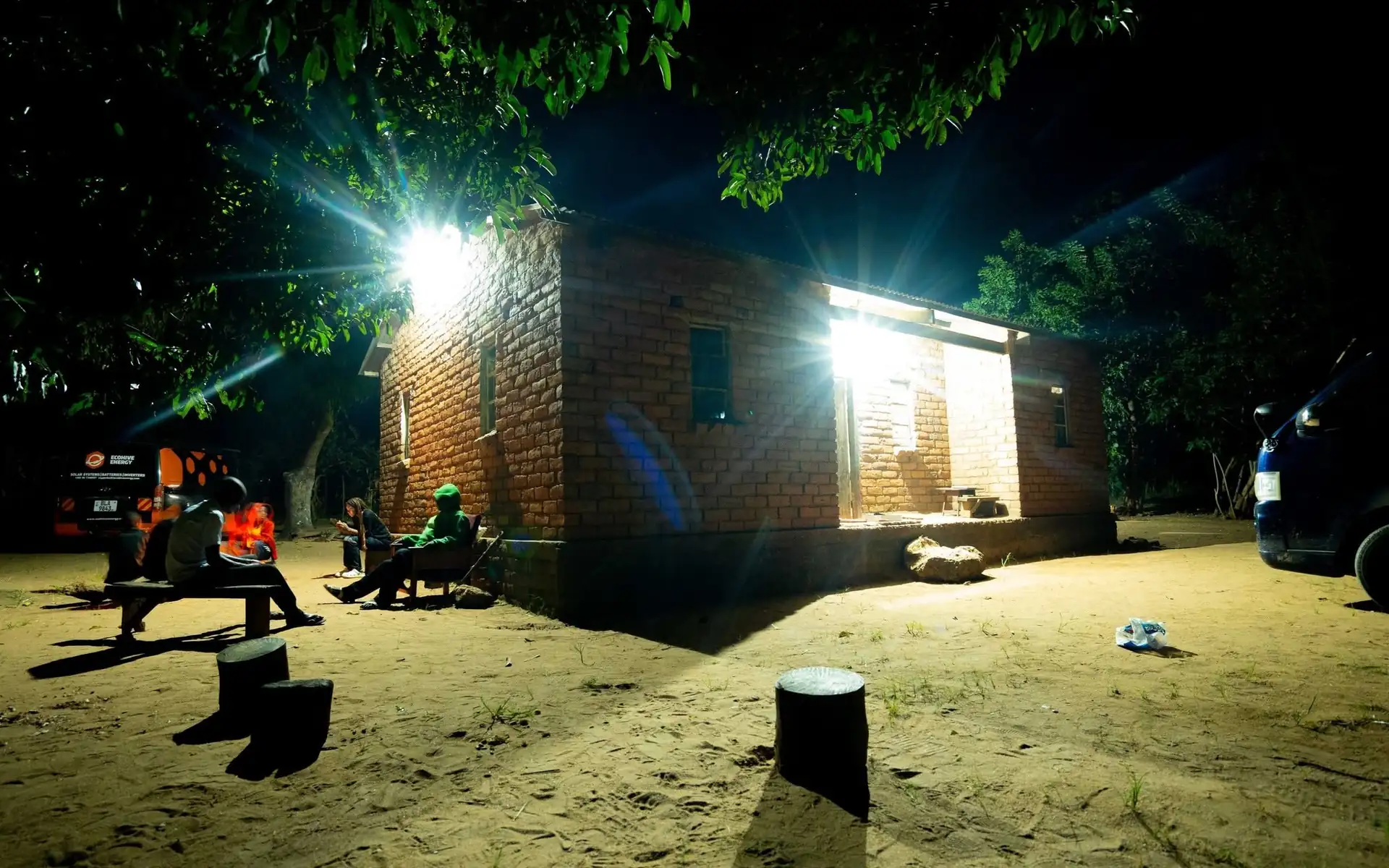 A home in Lazaro Village lit by solar power at night, with residents sitting outside