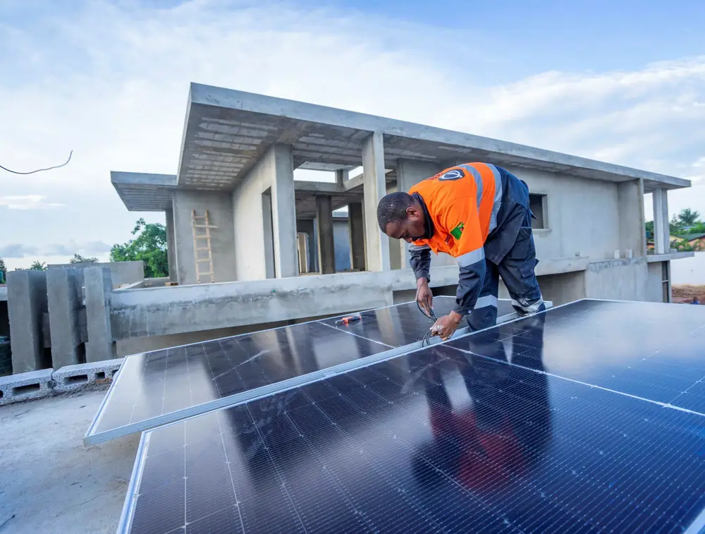 An EcoHive installer bolting down solar panels on the roof of a new house